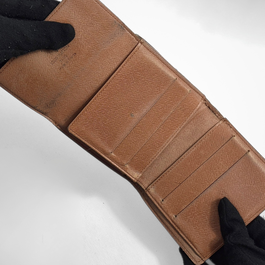 Brown leather wallet held by black-gloved hands on a white background