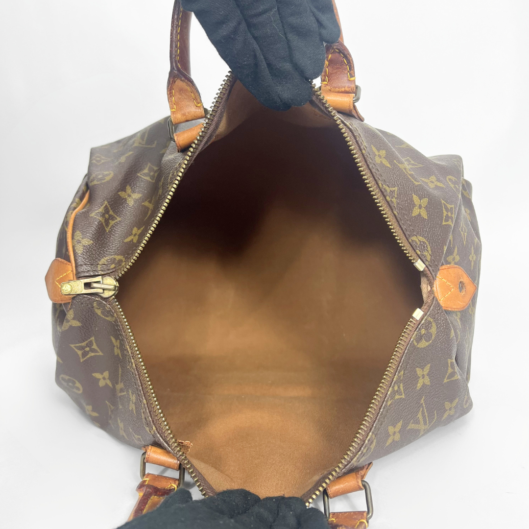 Brown monogram handbag with gold accents on a white background