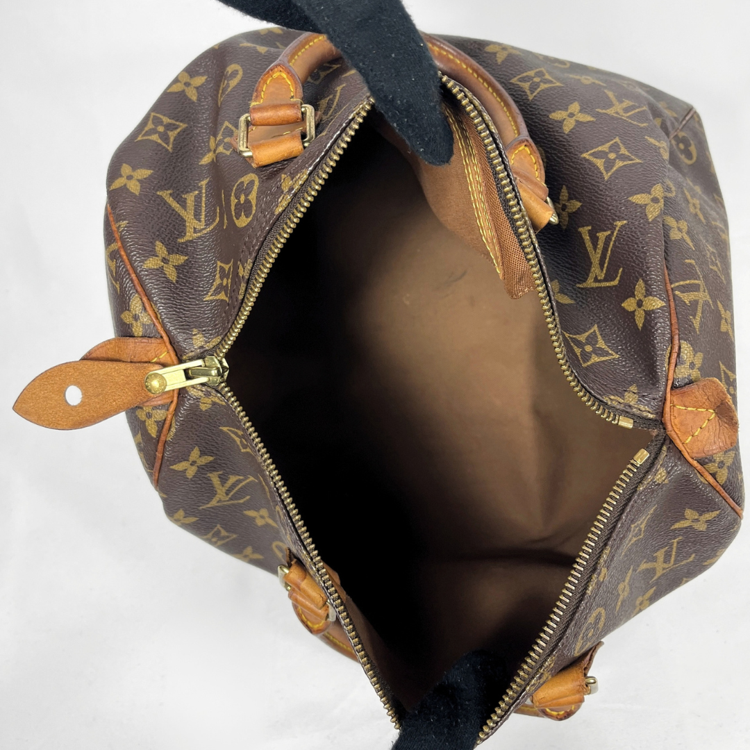 Louis Vuitton monogram canvas shoulder bag shown open from above, revealing a brown interior, gold-tone zippers, and tan leather trim on a white background.