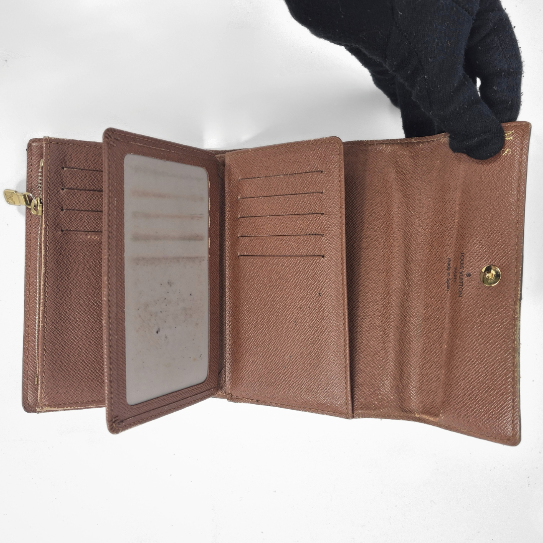 Brown leather wallet with gold zipper held open by a gloved hand on a white background
