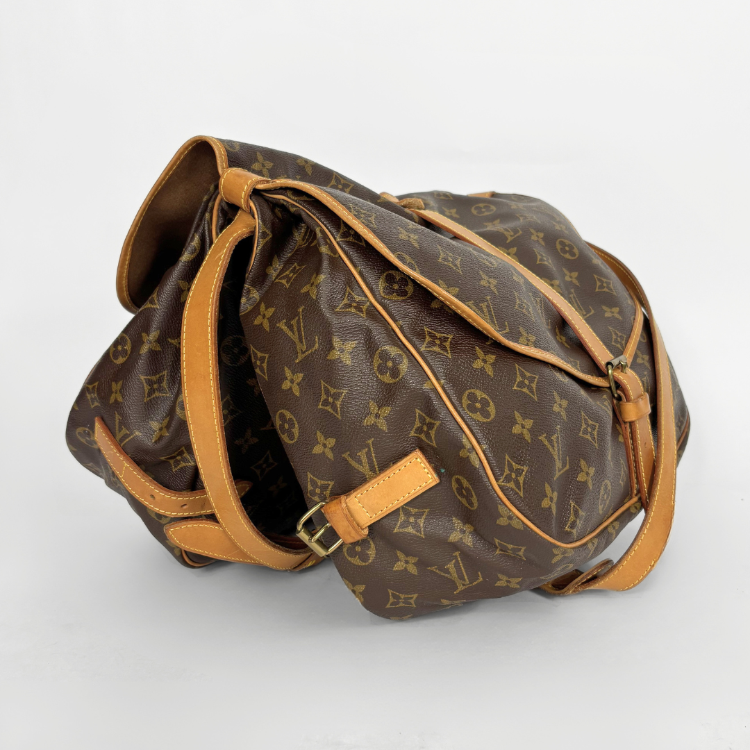 Brown monogram handbag with tan leather strap on a white background