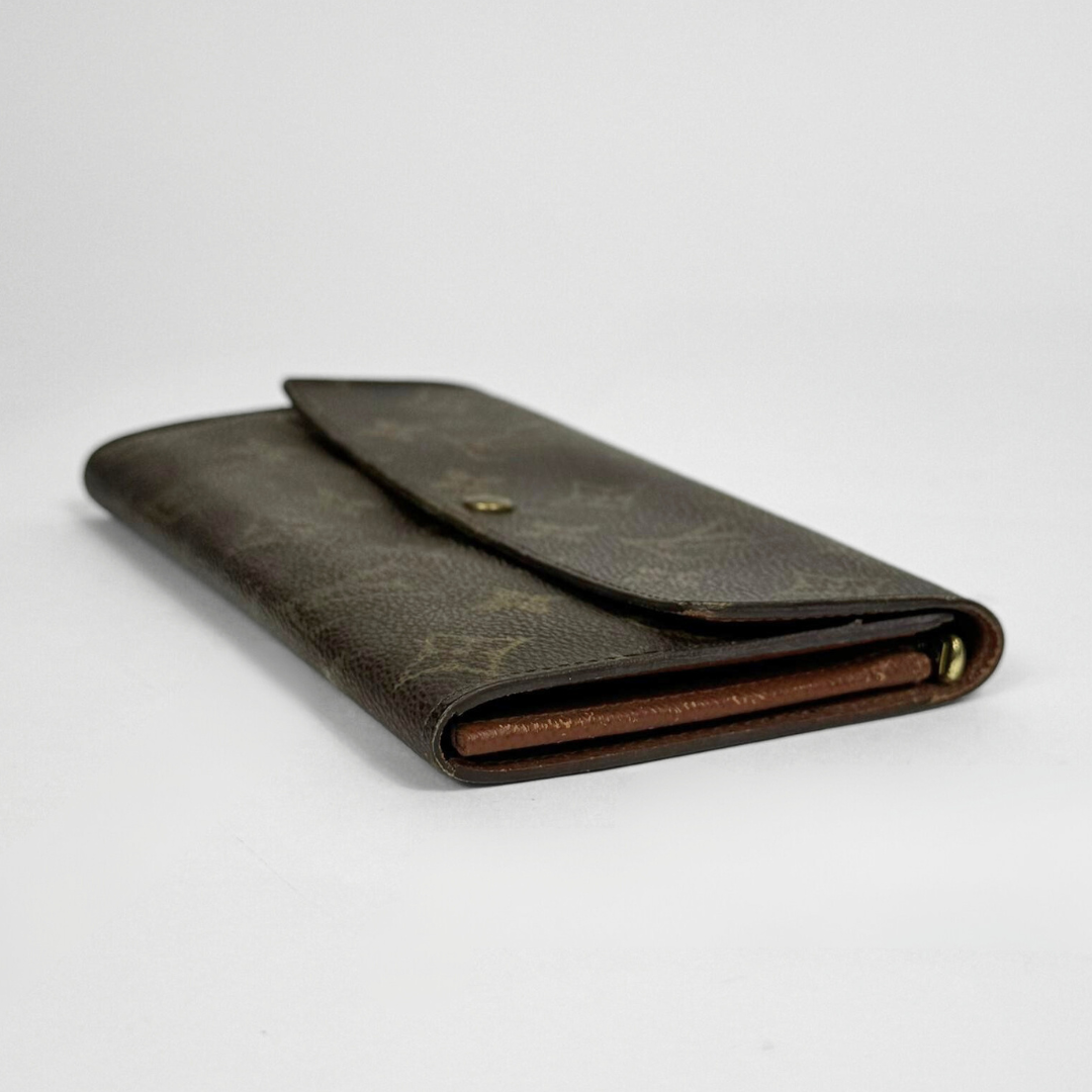 Brown wallet with gold monogram pattern on a white background