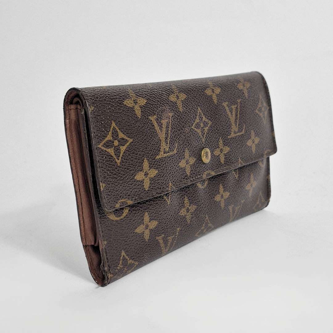 Louis Vuitton wallet with monogram pattern on a light gray background