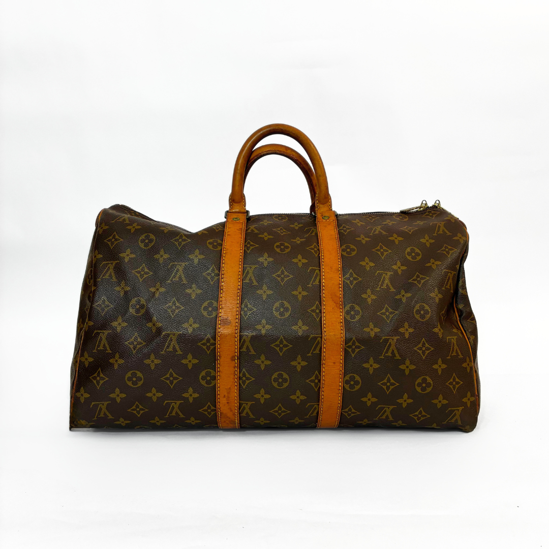 Brown travel bag with tan handles and trim on a white background