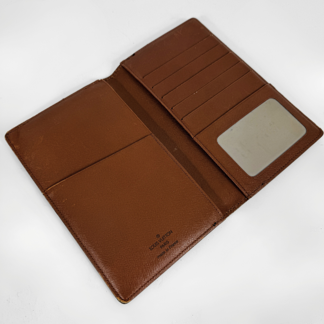 An open brown textured leather wallet with multiple card slots, a document pocket, and an ID window, photographed on a white background.