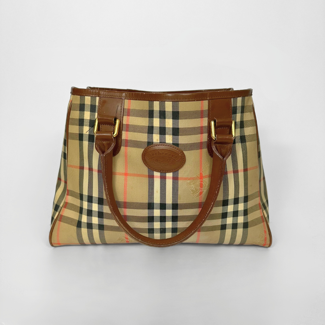 Plaid handbag with brown leather handles on a light gray background