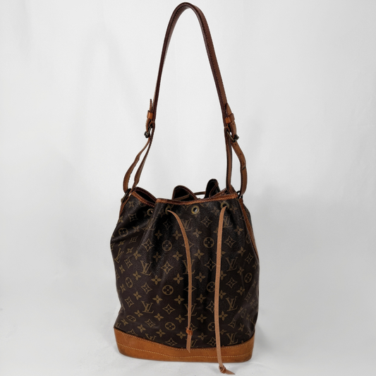 Louis Vuitton monogram canvas bucket bag with brown leather trim and shoulder strap, shown against a plain white background.