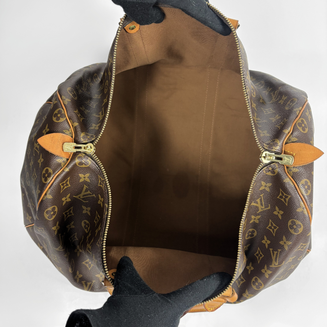 Louis Vuitton monogram canvas duffel bag shown open from the top, with a brown interior, gold-tone zippers, and tan leather accents on a light gray background.