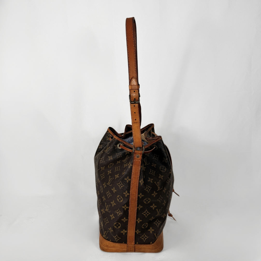 A Louis Vuitton monogram canvas bucket bag with brown leather trim and a single shoulder strap, photographed against a plain white background.