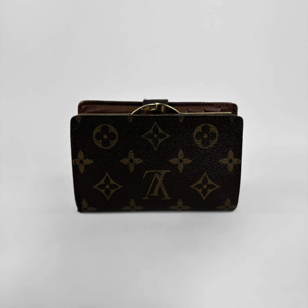 A Louis Vuitton monogram canvas clutch wallet in dark brown with gold-tone hardware, shown against a neutral light gray background.