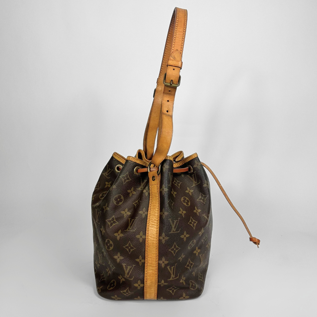 Brown monogram handbag with tan leather strap on a light gray background