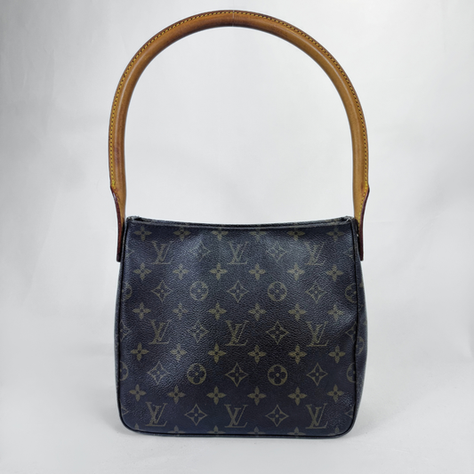 A Louis Vuitton shoulder bag in dark navy monogram canvas with a tan leather top handle, photographed against a light gray studio background.