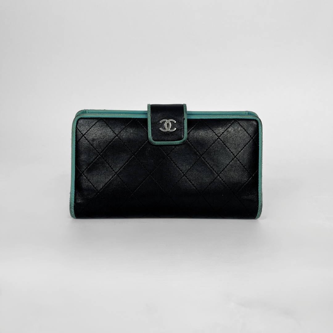 A black quilted leather clutch wallet with a silver-tone interlocking CC logo on the front flap, accented by a teal-green trim.