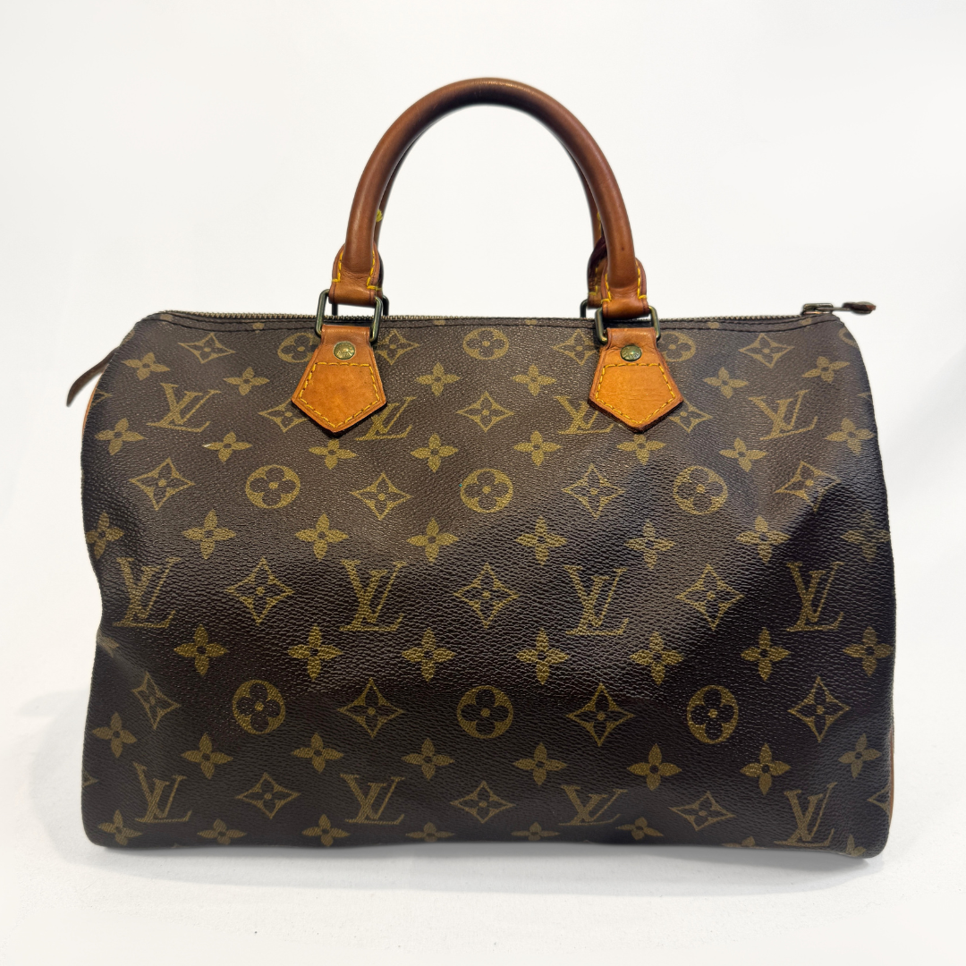 A Louis Vuitton monogram canvas Speedy handbag with brown leather handles and trim, photographed against a plain white background.