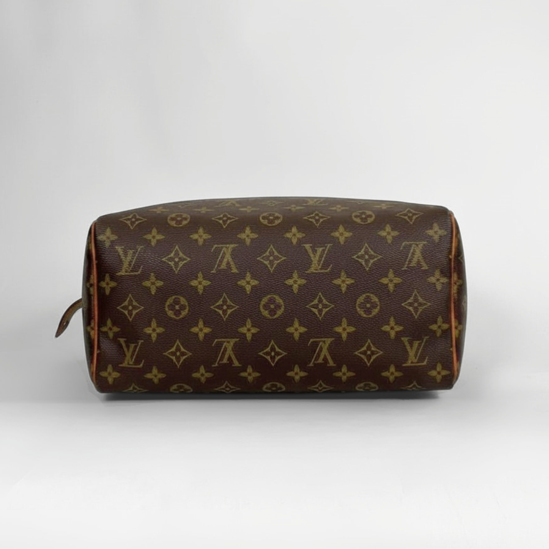 A Louis Vuitton monogram toiletry bag in brown coated canvas with gold-tone monogram print, shown from a side profile view against a light gray background.