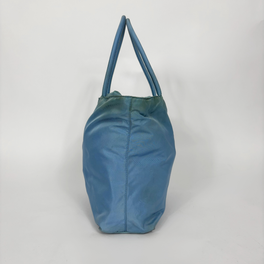 Prada light blue nylon tote bag with matching top handles and the signature enamel triangle logo.