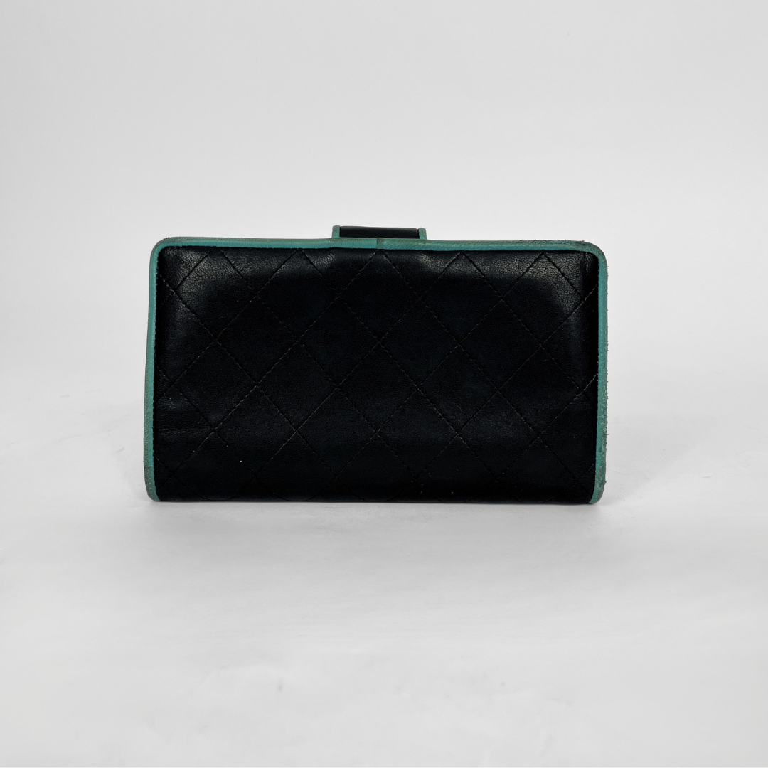 A black quilted leather clutch bag with a mint green trim, photographed against a neutral light gray background.