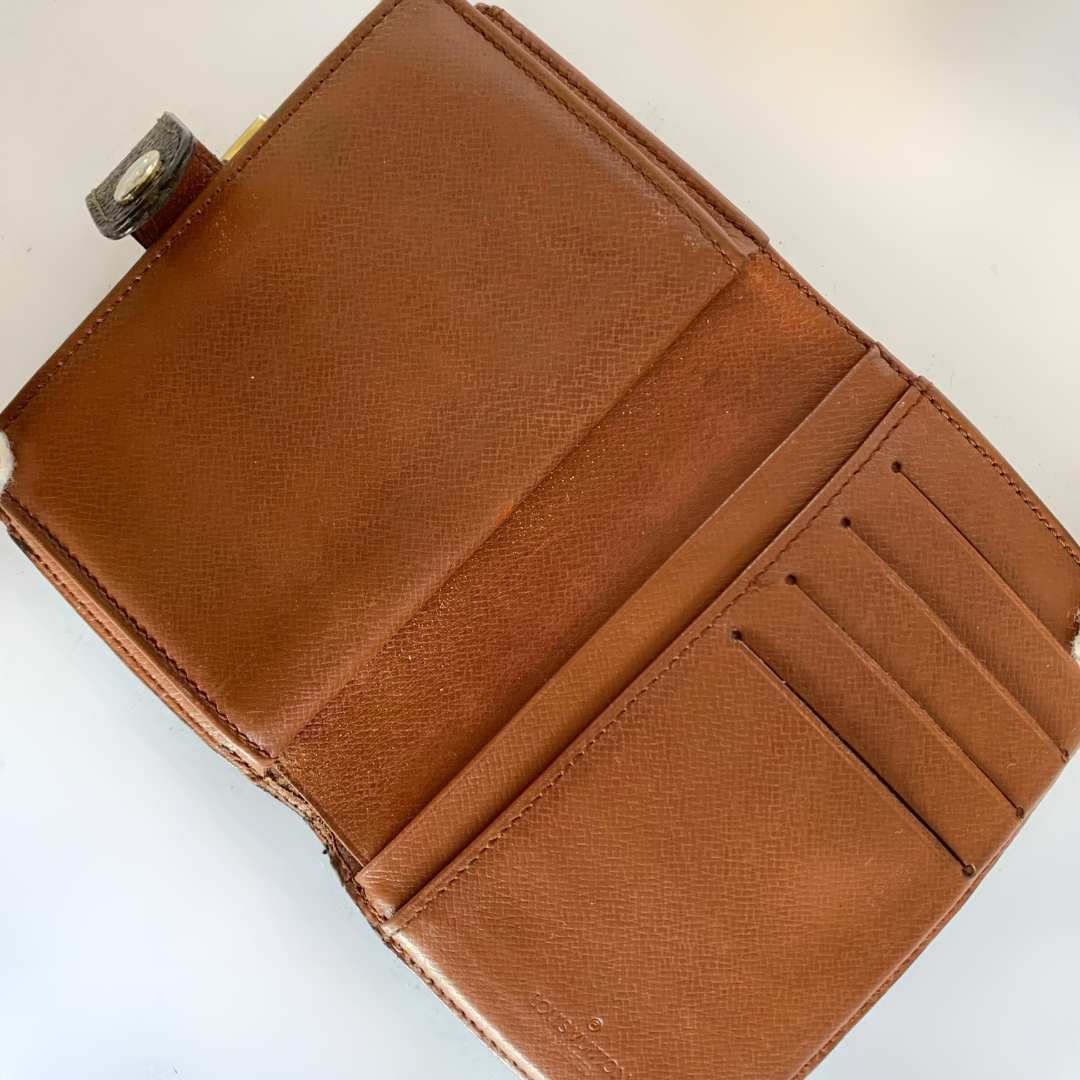 A brown textured leather wallet shown open, displaying its interior card slots and pocket compartments on a plain white background.