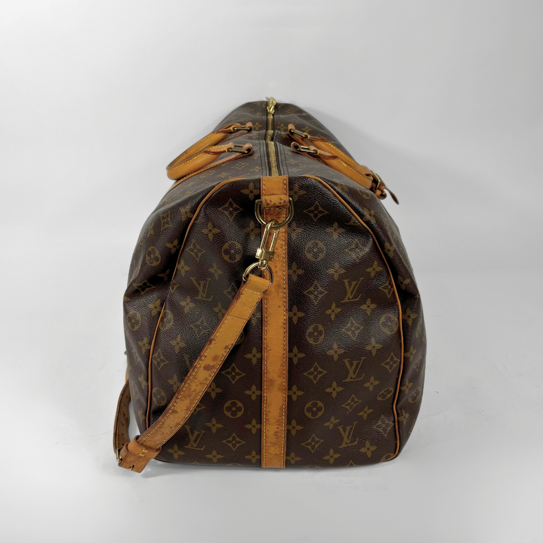 Brown monogrammed travel bag with tan leather straps on a white background