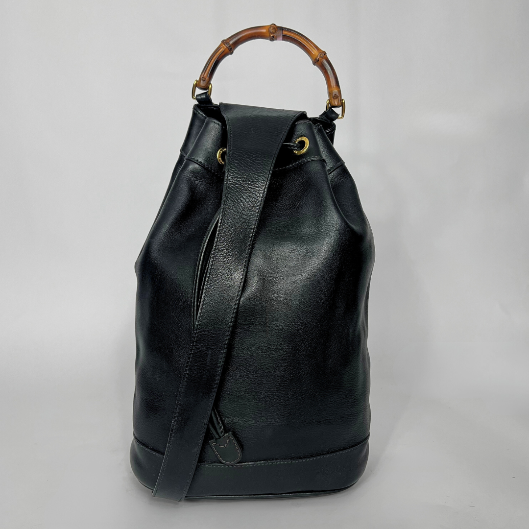 Black leather backpack with bamboo handle on a gray background