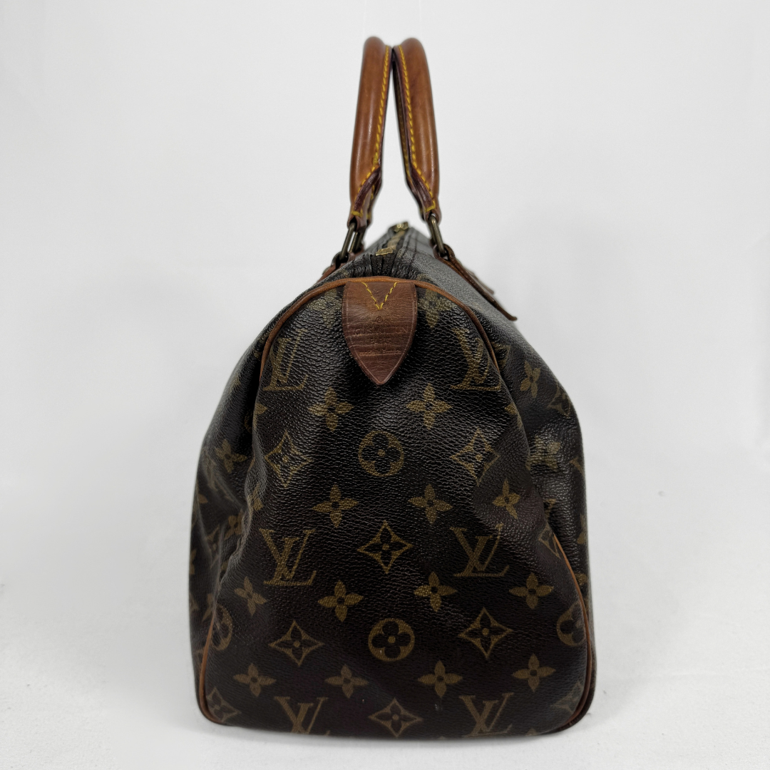A Louis Vuitton monogram Speedy bag in dark brown coated canvas with tan leather handles and trim, photographed against a plain white background.