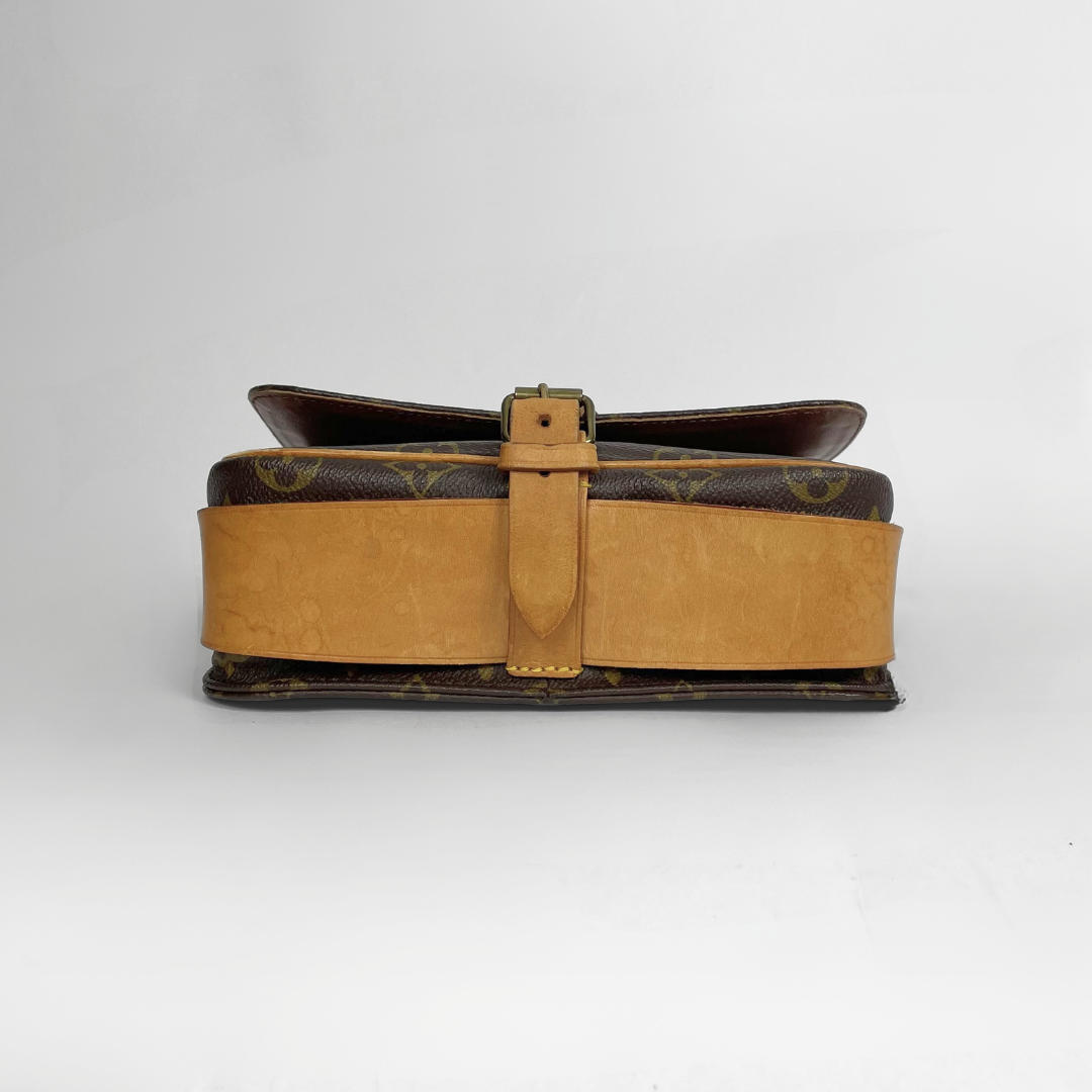 A vintage Louis Vuitton shoulder bag in brown monogram canvas with a wide tan leather strap and a matching tan leather buckle strap, photographed against a light gray background.