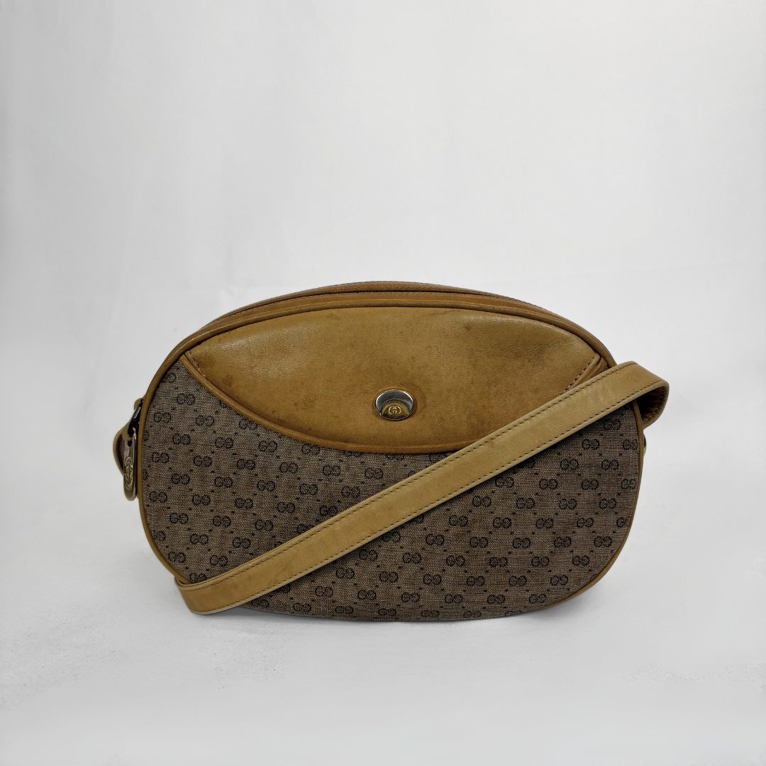 A vintage Gucci shoulder bag in brown GG Supreme canvas with a tan suede front panel and matching tan strap, featuring a central gold-tone logo clasp.