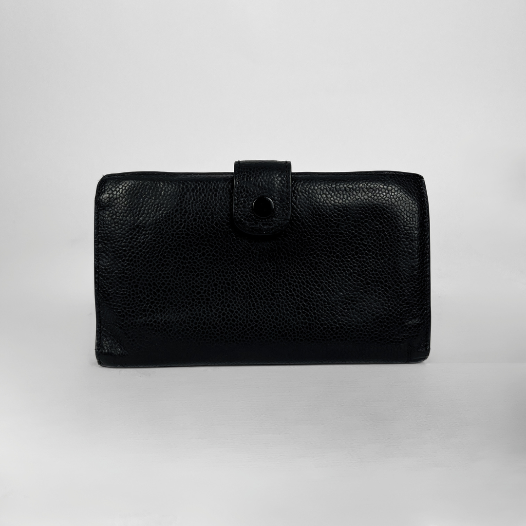 A black pebbled leather clutch wallet with a snap-button strap closure, photographed against a neutral light gray background.