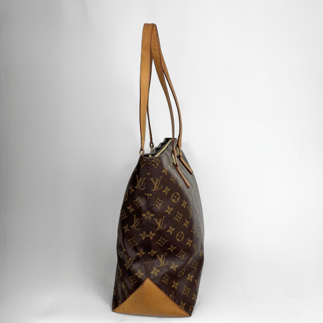 A Louis Vuitton monogram canvas tote bag with tan leather trim and shoulder straps, photographed against a neutral light gray background.