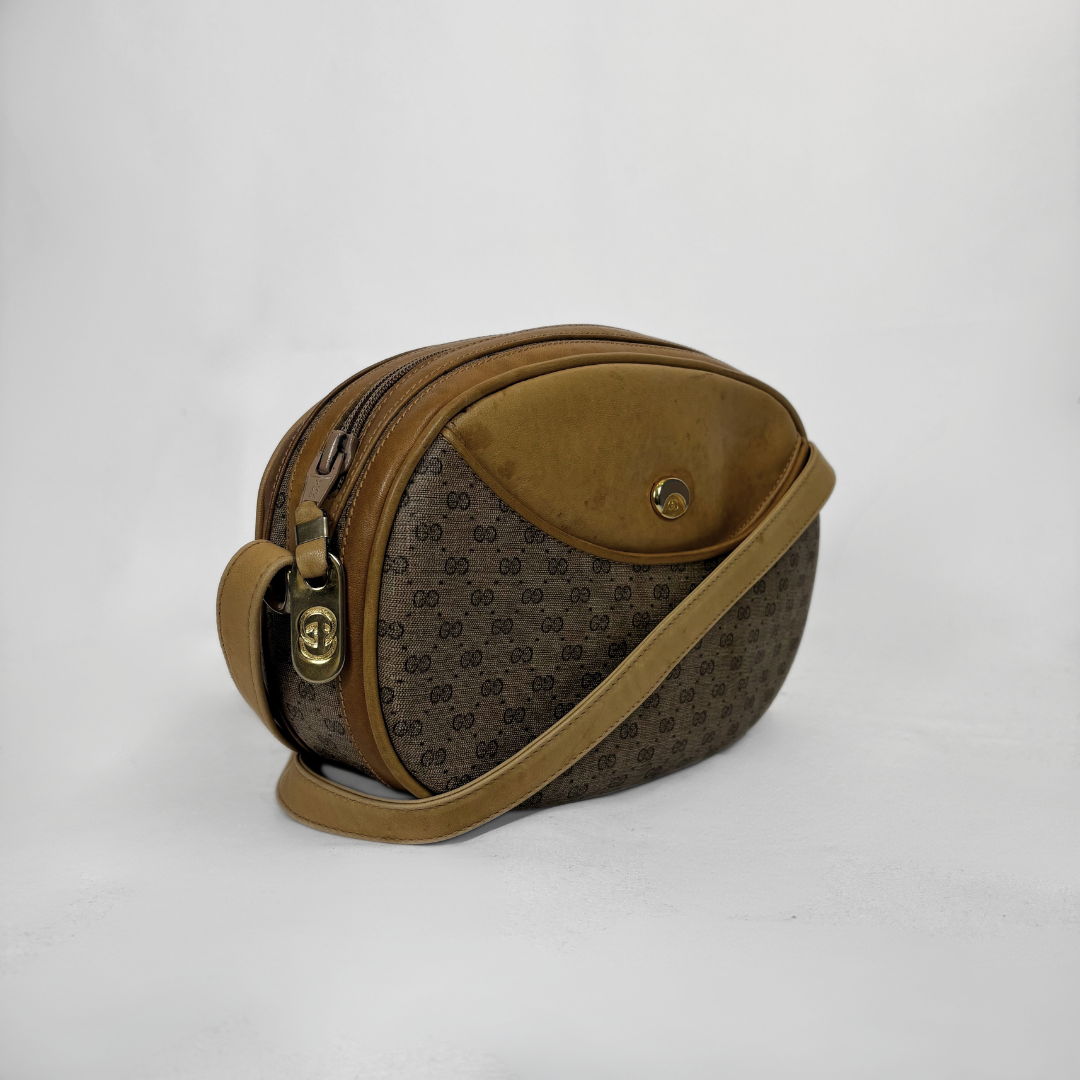A vintage Gucci shoulder bag in brown GG Supreme canvas with tan leather trim and a matching shoulder strap, photographed on a light gray background.