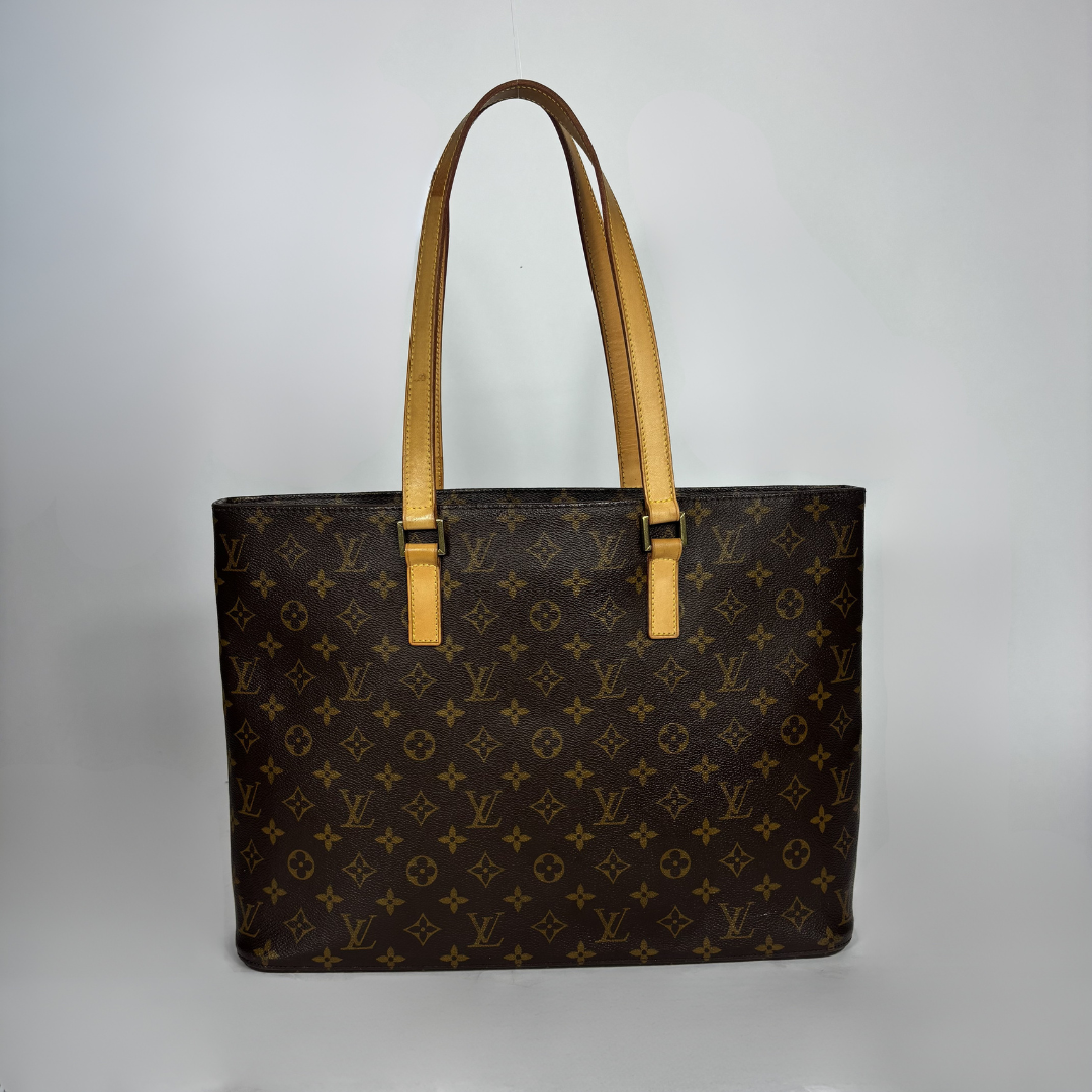 A Louis Vuitton tote bag in brown monogram canvas with tan leather shoulder straps, photographed against a neutral light gray background.