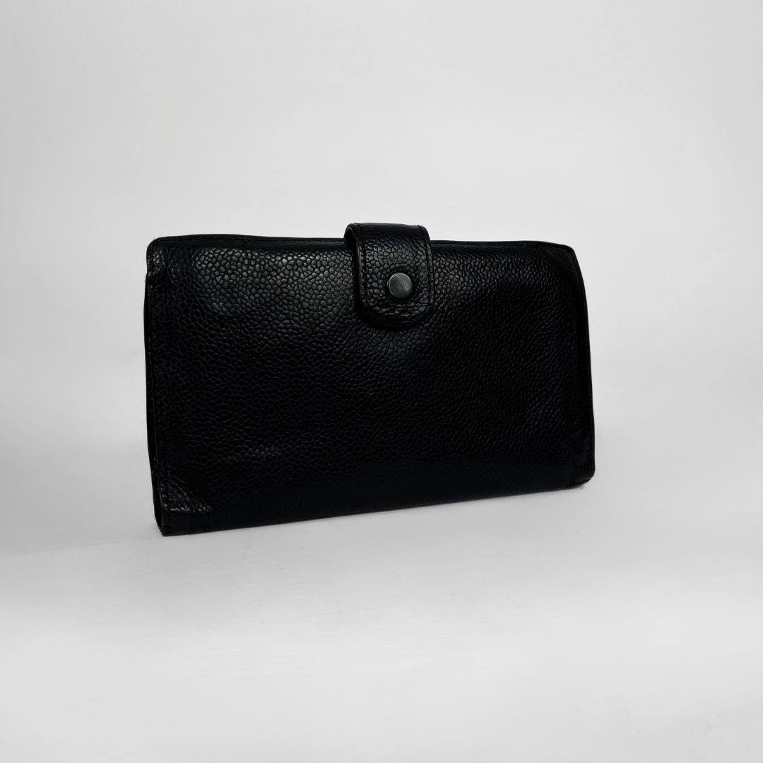A black pebbled leather clutch wallet with a snap-button strap closure, shown on a light gray studio background.