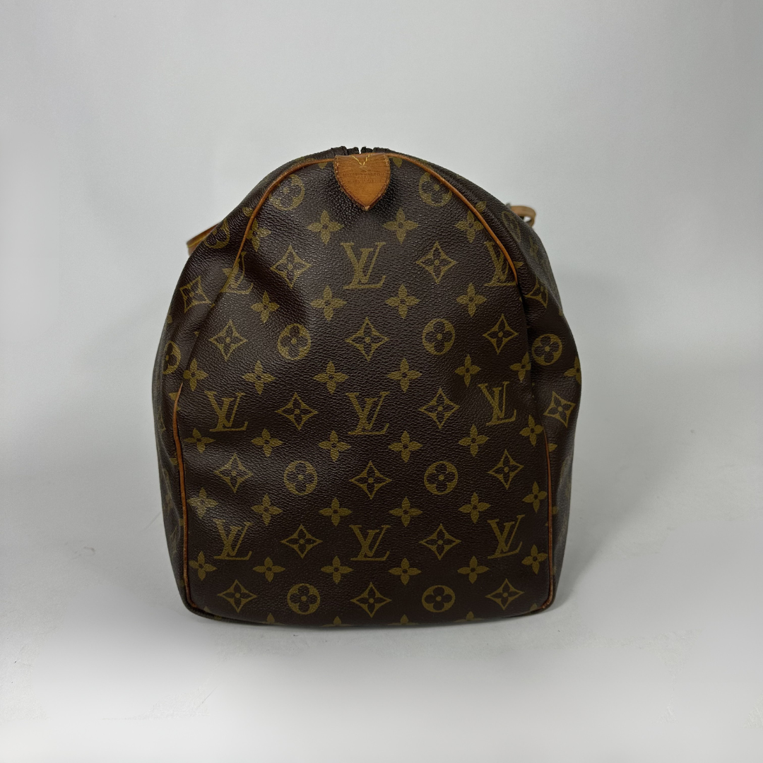 Brown monogram patterned duffel bag with tan leather straps on a white background