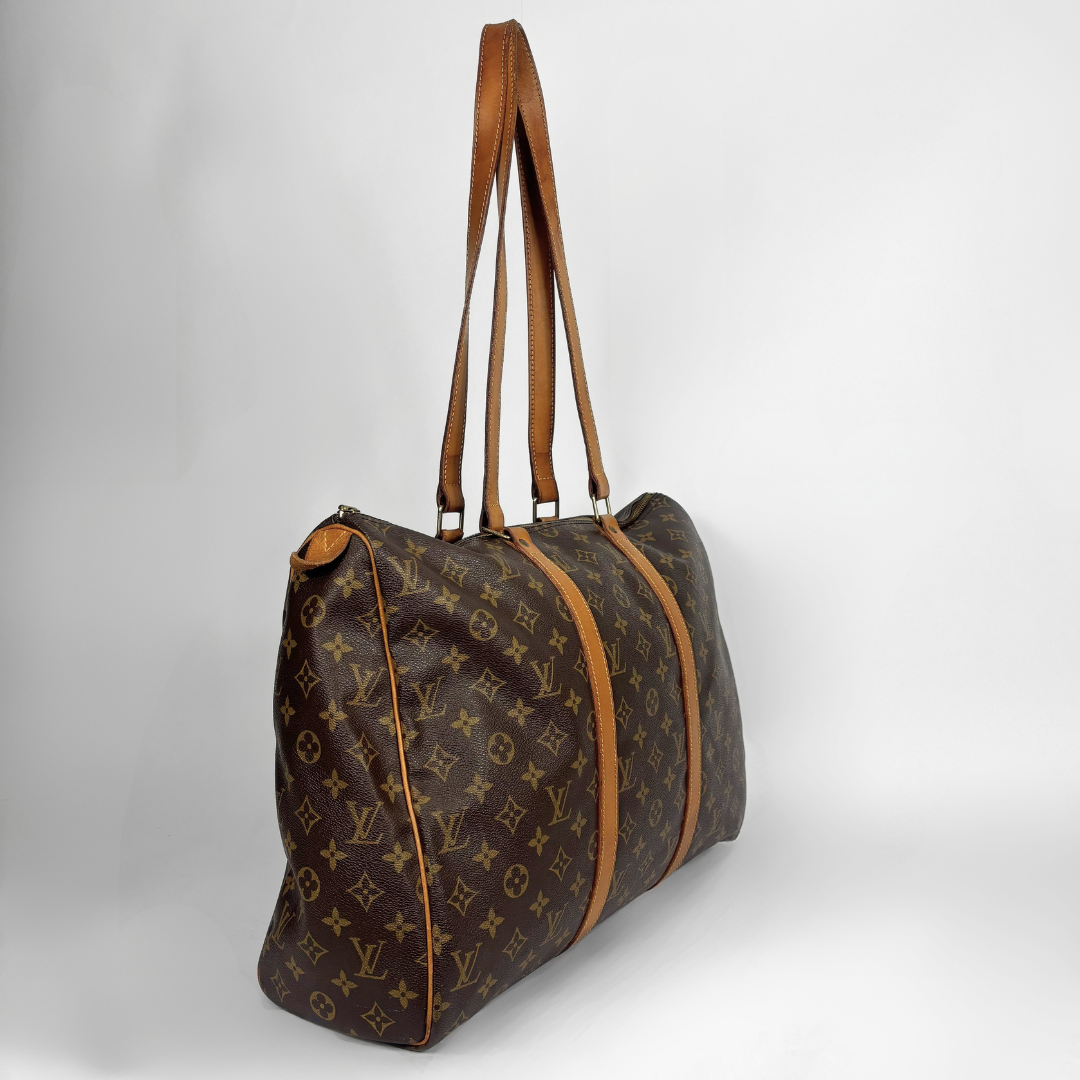 A Louis Vuitton monogram canvas duffel bag with brown leather trim and shoulder straps, photographed on a light gray studio background.