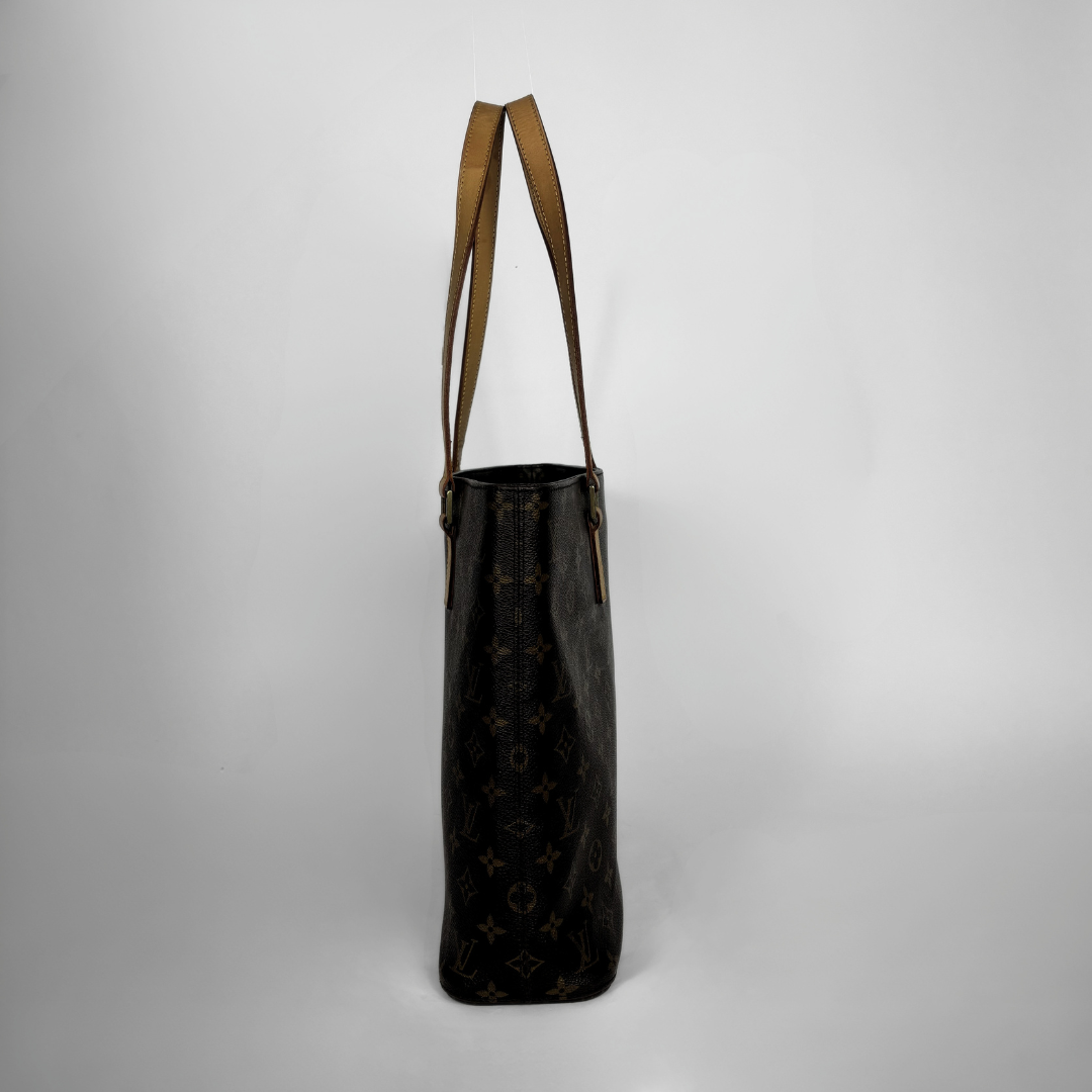 A Louis Vuitton monogram canvas tote bag in dark brown with tan leather shoulder straps, shown against a neutral light gray background.