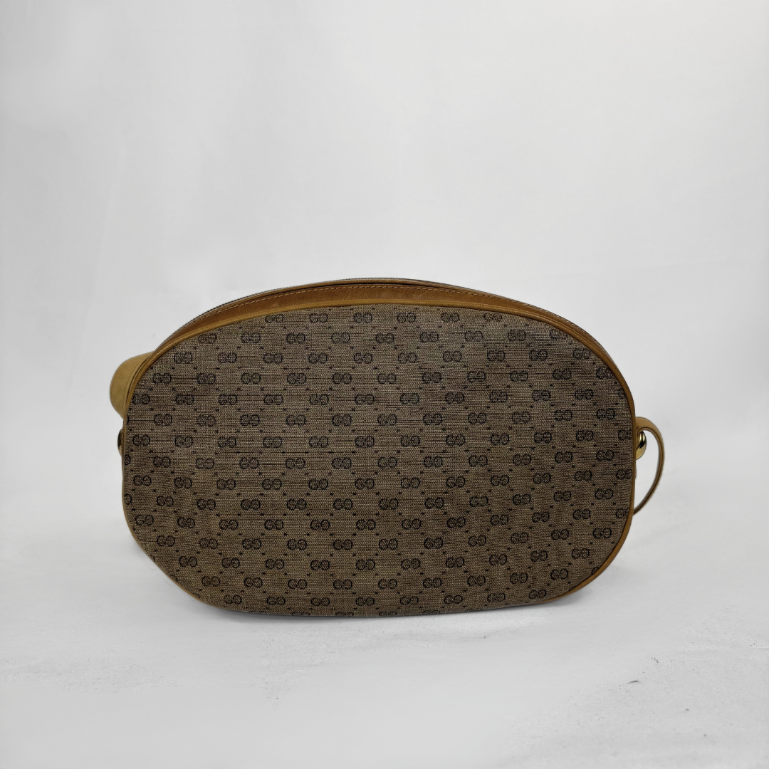 A brown monogram canvas pouch with gold-toned leather trim and a side loop handle, photographed against a plain white background.