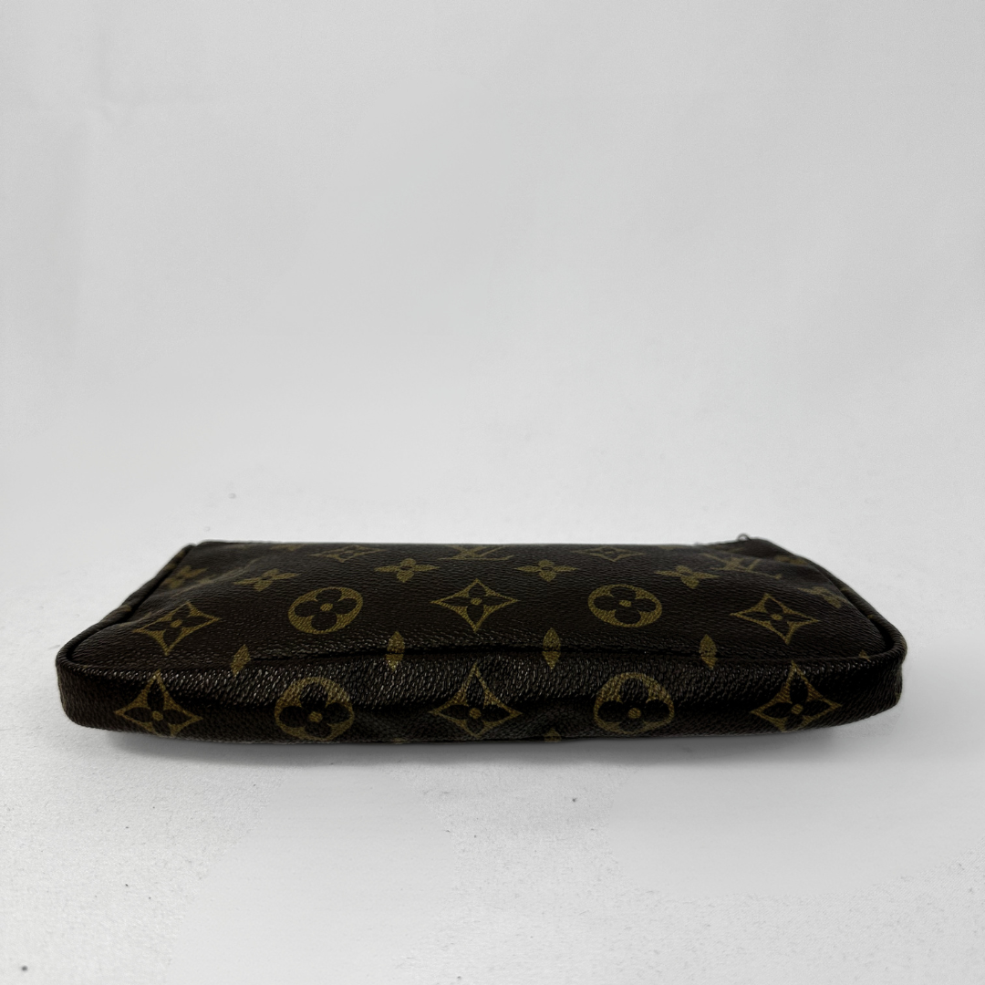 A Louis Vuitton monogram canvas pouch in dark brown and tan, featuring the classic LV logo pattern, photographed on a light gray background.