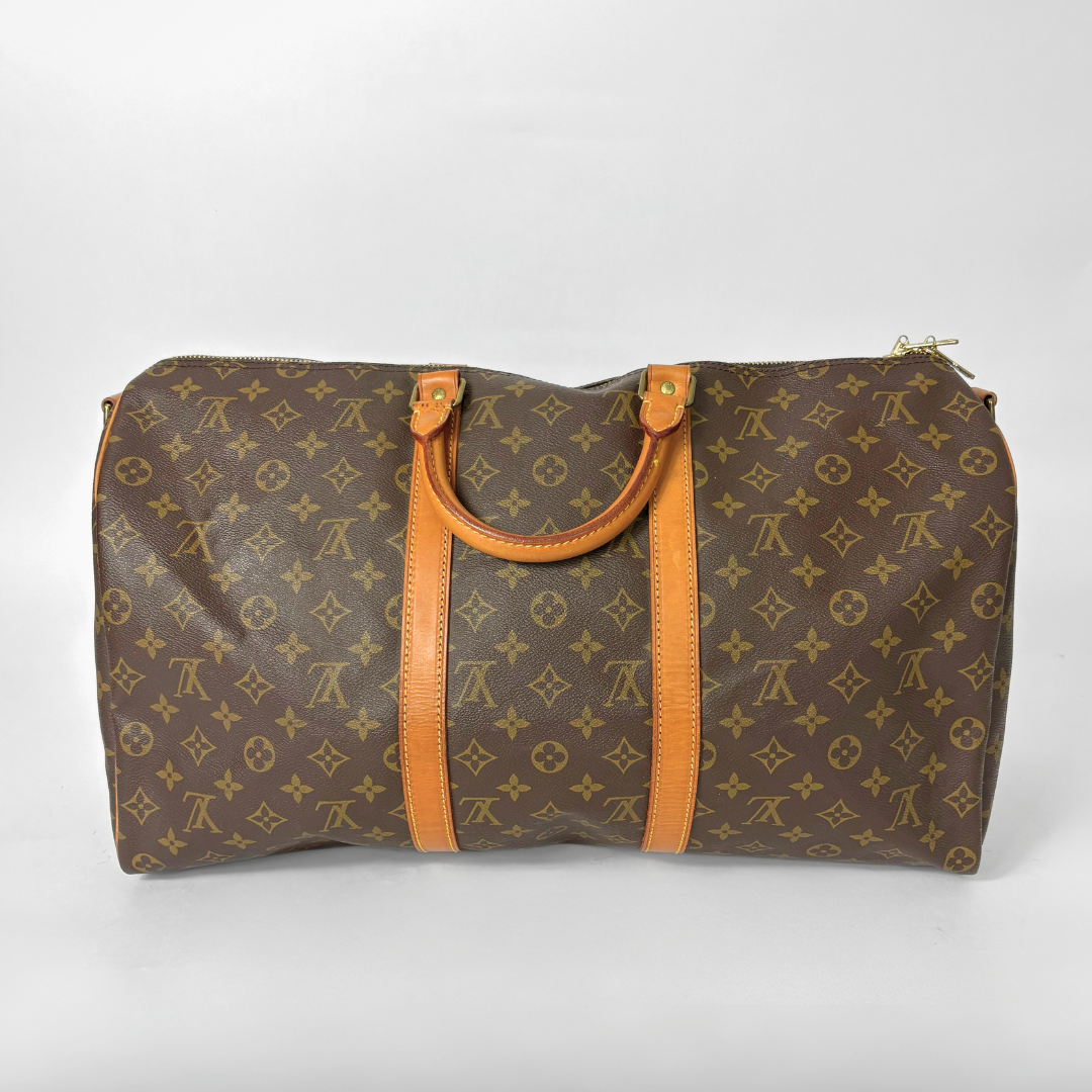 Brown monogram patterned bag with orange leather handles on a white background