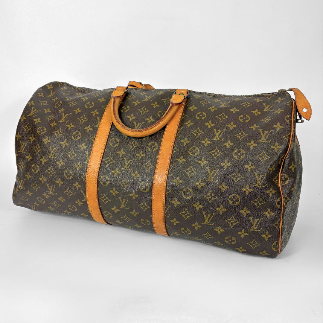 Louis Vuitton monogram travel bag with brown handles on a white background