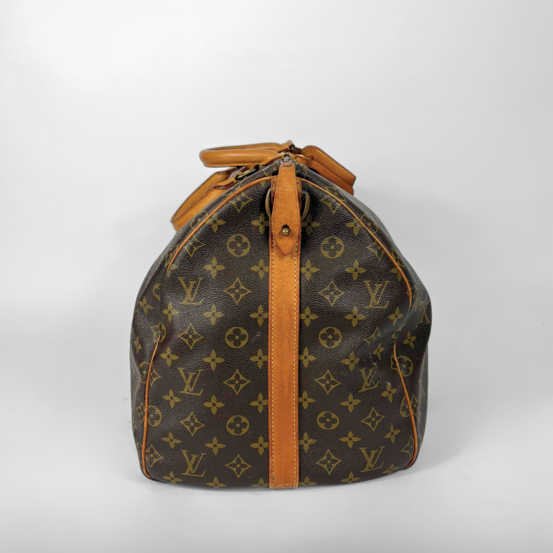 Louis Vuitton monogram travel bag with brown handles on a white background