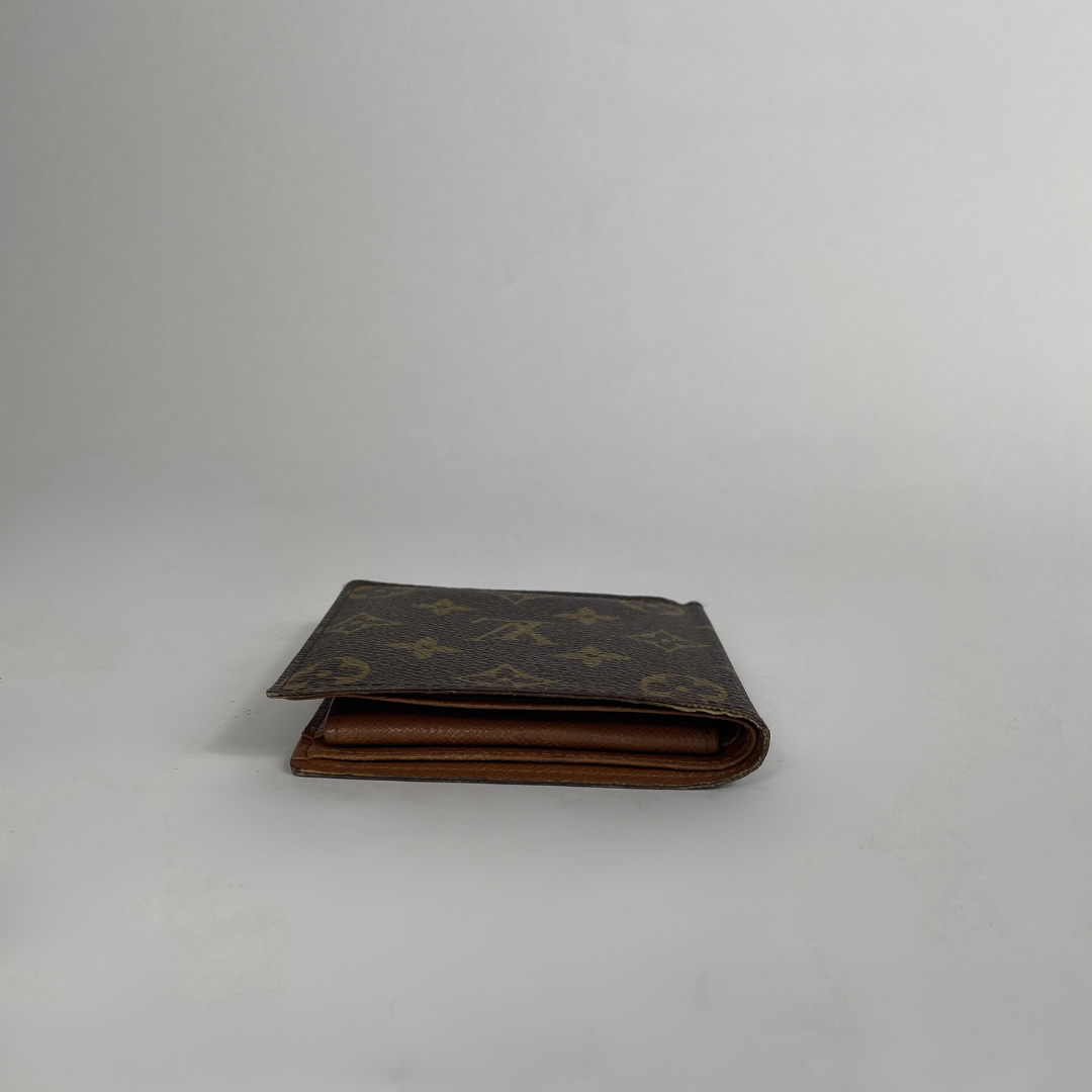 A classic Louis Vuitton monogram canvas bifold wallet in dark brown with tan monogram motifs and a brown leather interior, shown closed on a light gray background.