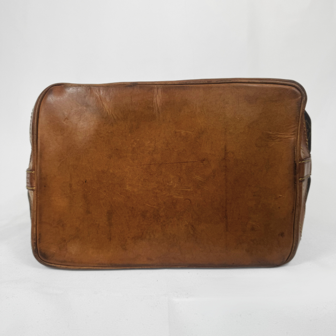 A vintage brown leather messenger bag shown from the back, featuring a rectangular shape with rounded corners and visible wear and scuffs on the leather surface, set against a plain white background.
