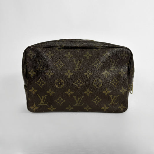 A Louis Vuitton toiletry bag in classic brown monogram canvas, photographed against a neutral light gray background.