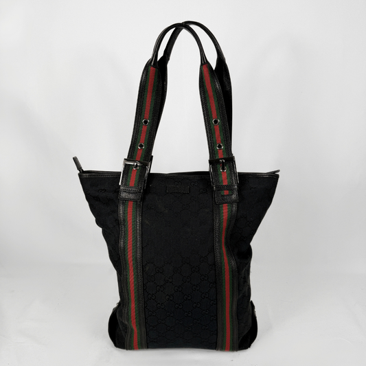 A black Gucci tote bag featuring the brand's signature green and red web stripe pattern on the handles and side panels, set against a plain white background.