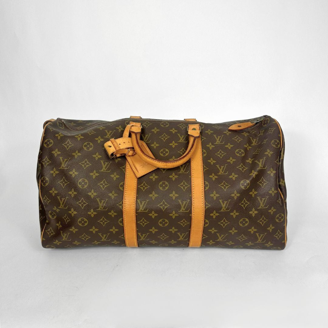 Brown monogram duffel bag with tan leather handles on a white background