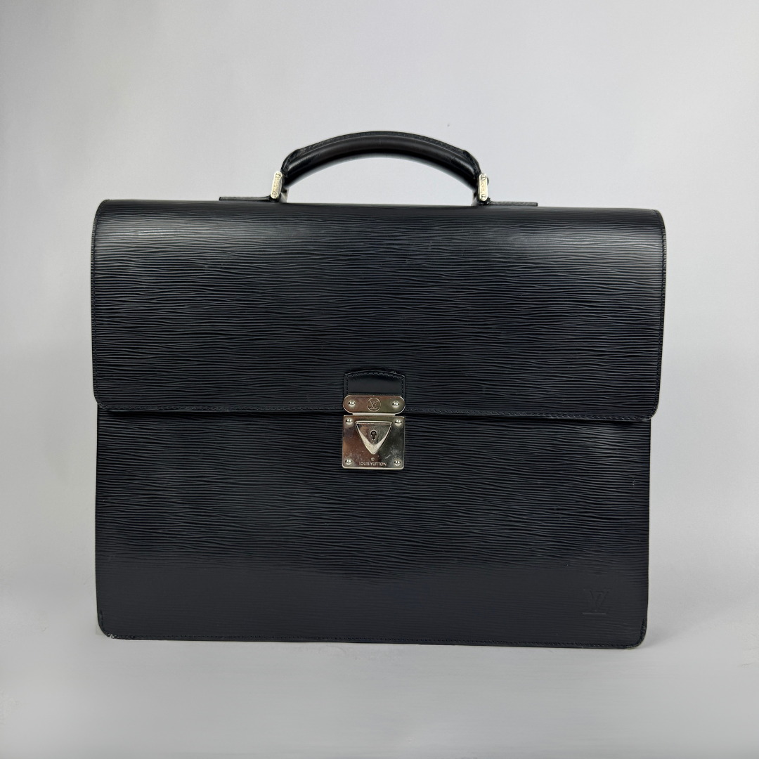 A black textured leather Louis Vuitton briefcase with a top handle and a silver-toned metal clasp on a light gray background.