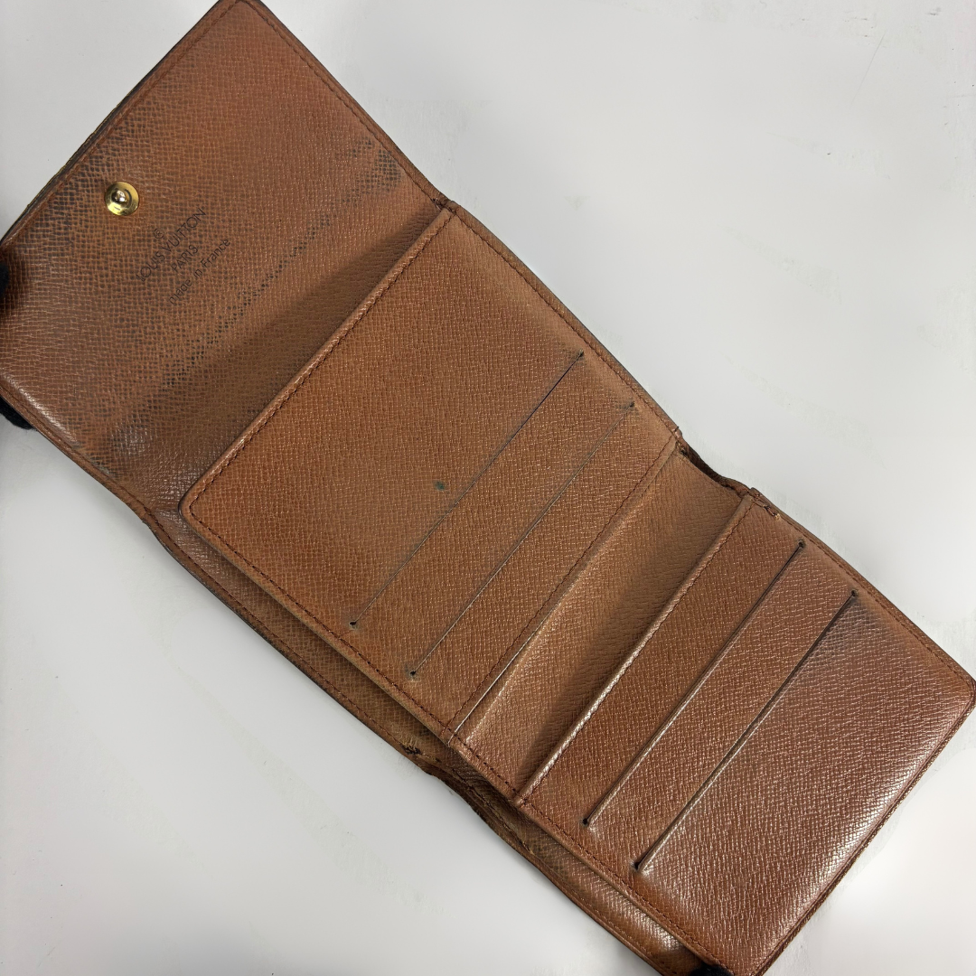 An open brown leather wallet with multiple card slots and an interior pocket, photographed on a plain light background.