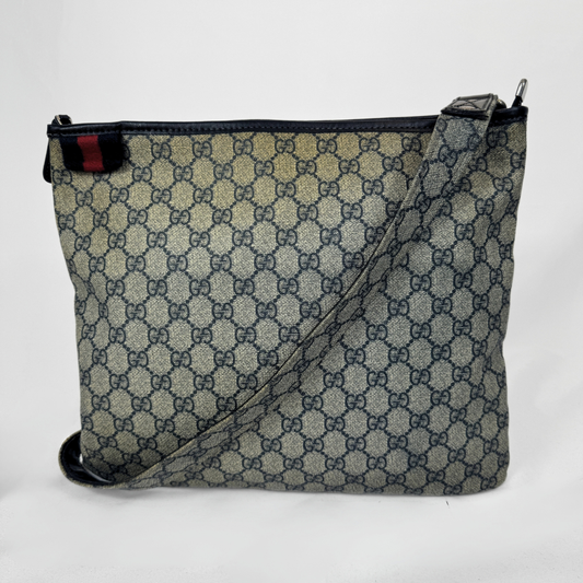 Gucci GG Supreme Web Flat Messenger bag in signature monogram canvas with green and red Web detailing and leather trims, displayed on a light grey background.
