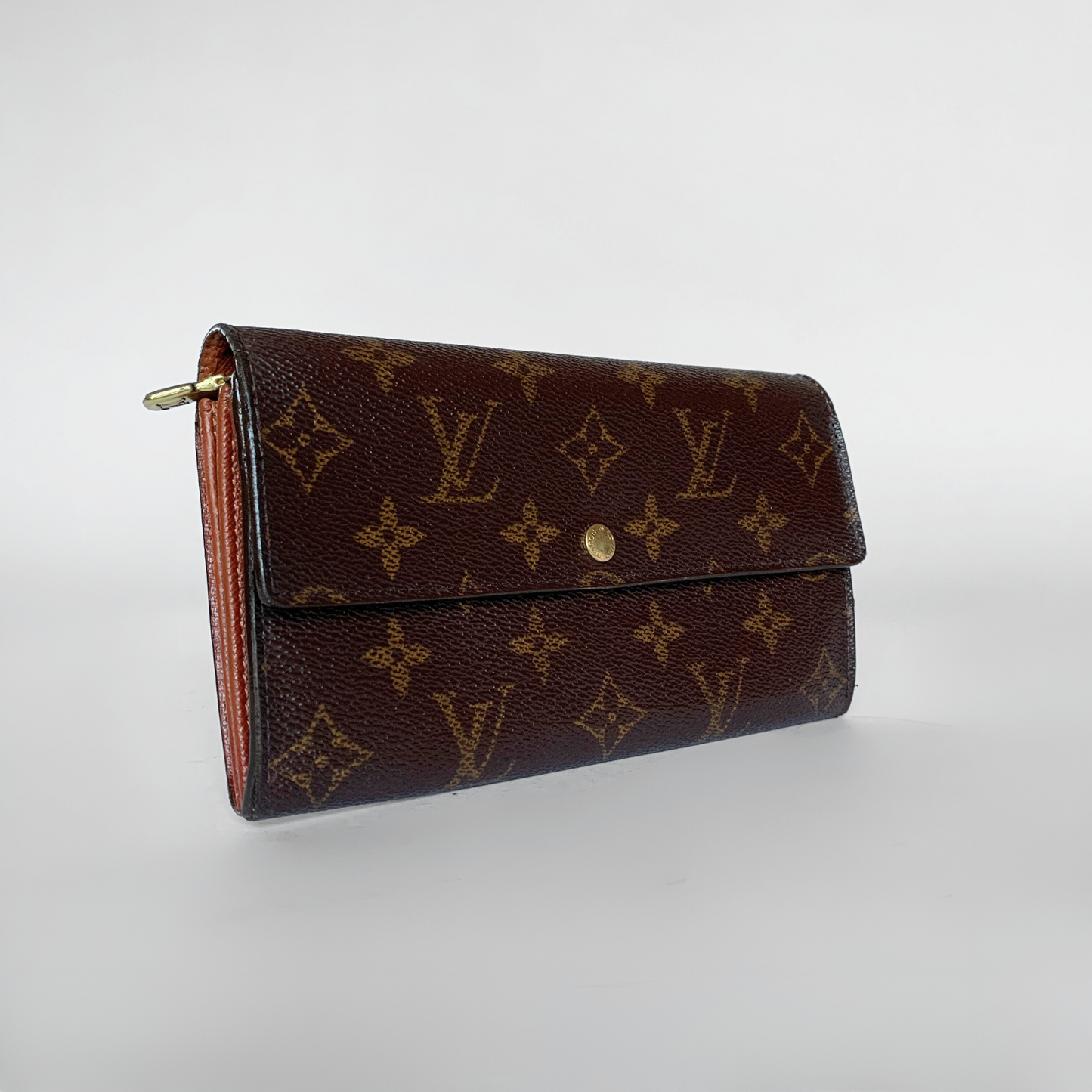 A Louis Vuitton monogram canvas wallet in dark brown with gold-tone hardware, photographed on a clean light gray studio background.