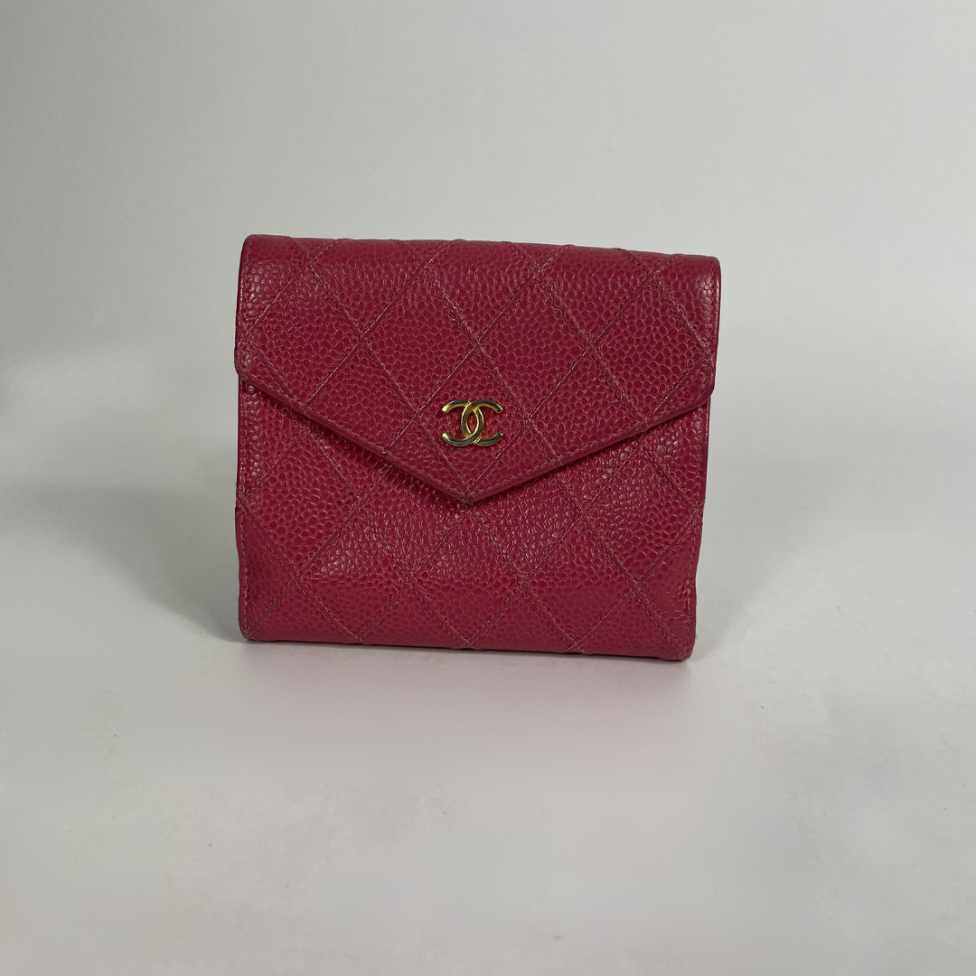 A vintage Chanel envelope wallet in red pebbled leather with a gold-tone interlocking CC logo, set against a plain light gray background.